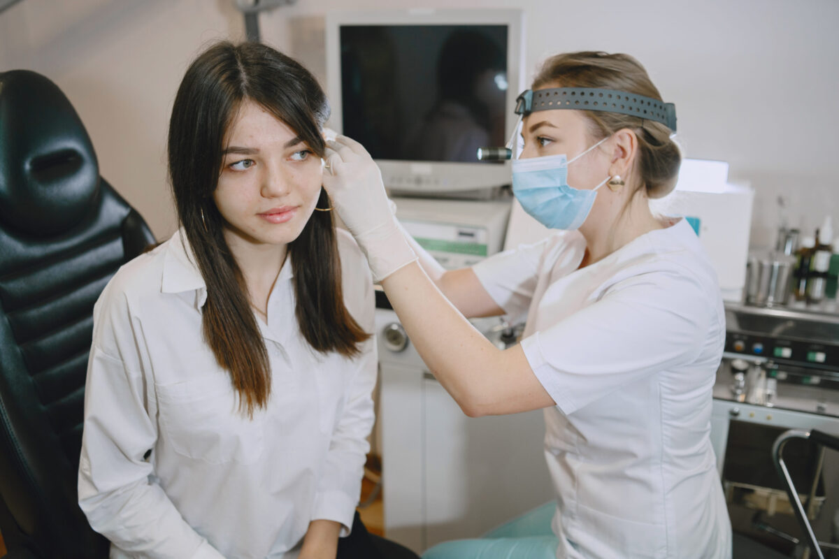 Woman patient in the medical office. Doctor in medical mask. Lor checks the woman' ears.